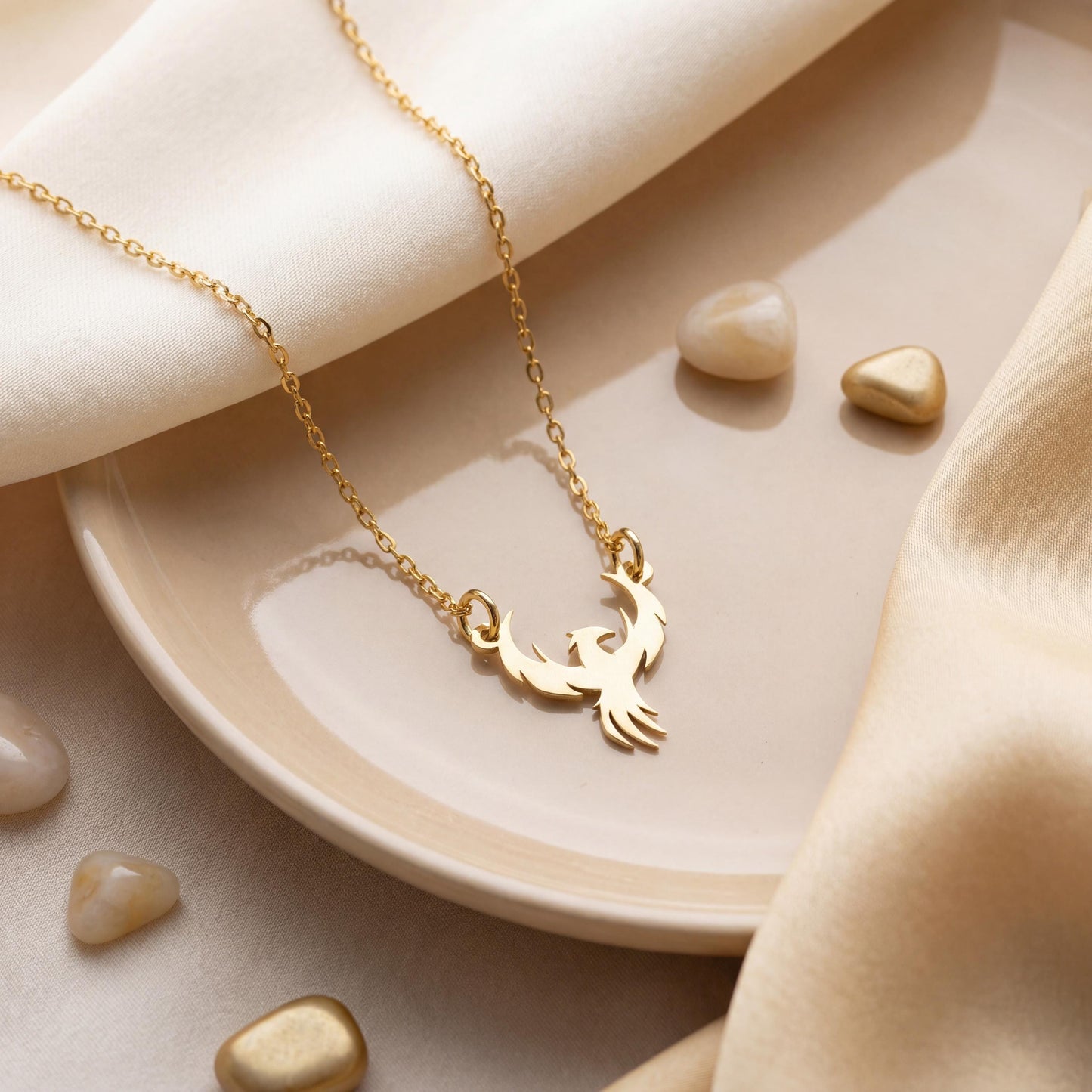 Minimalist gold phoenix pendant necklace worn on a woman's collarbone in warm sunlight, symbolizing rebirth and strength, ideal for Mothers Day gifting