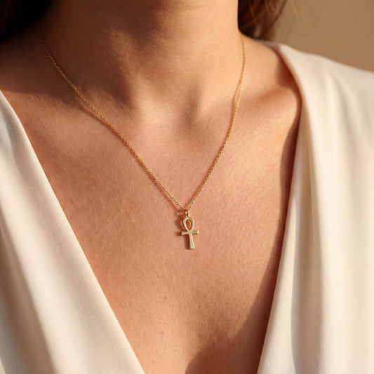 Minimalist Ankh necklace worn by a woman, dainty Egyptian cross key of life pendant resting on chest in natural sunlight, elegant everyday jewelry.