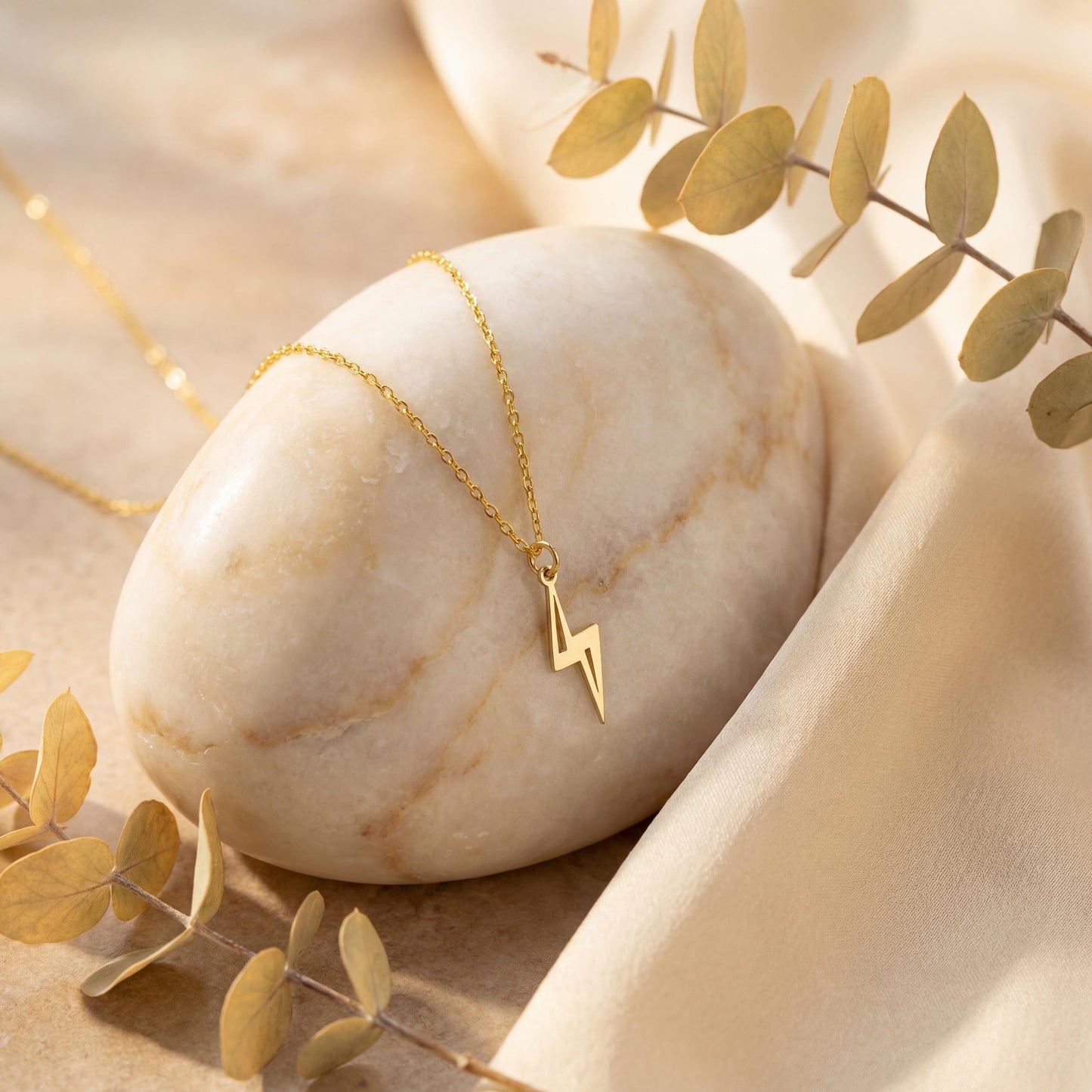 Close-up of a delicate minimalist 14k gold plated lightning bolt pendant necklace worn by a woman in a white shirt, glowing in soft sunlight.