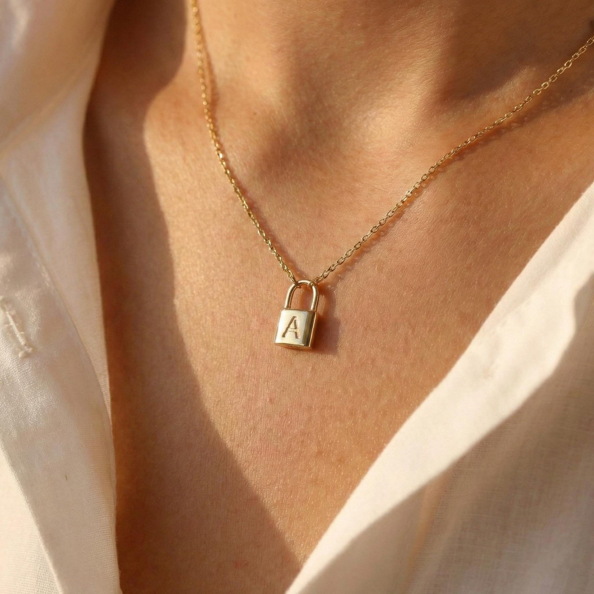 Gold padlock necklace with engraved initial letter A, dainty minimalist personalized jewelry gift for her, Mother's Day custom pendant on model.