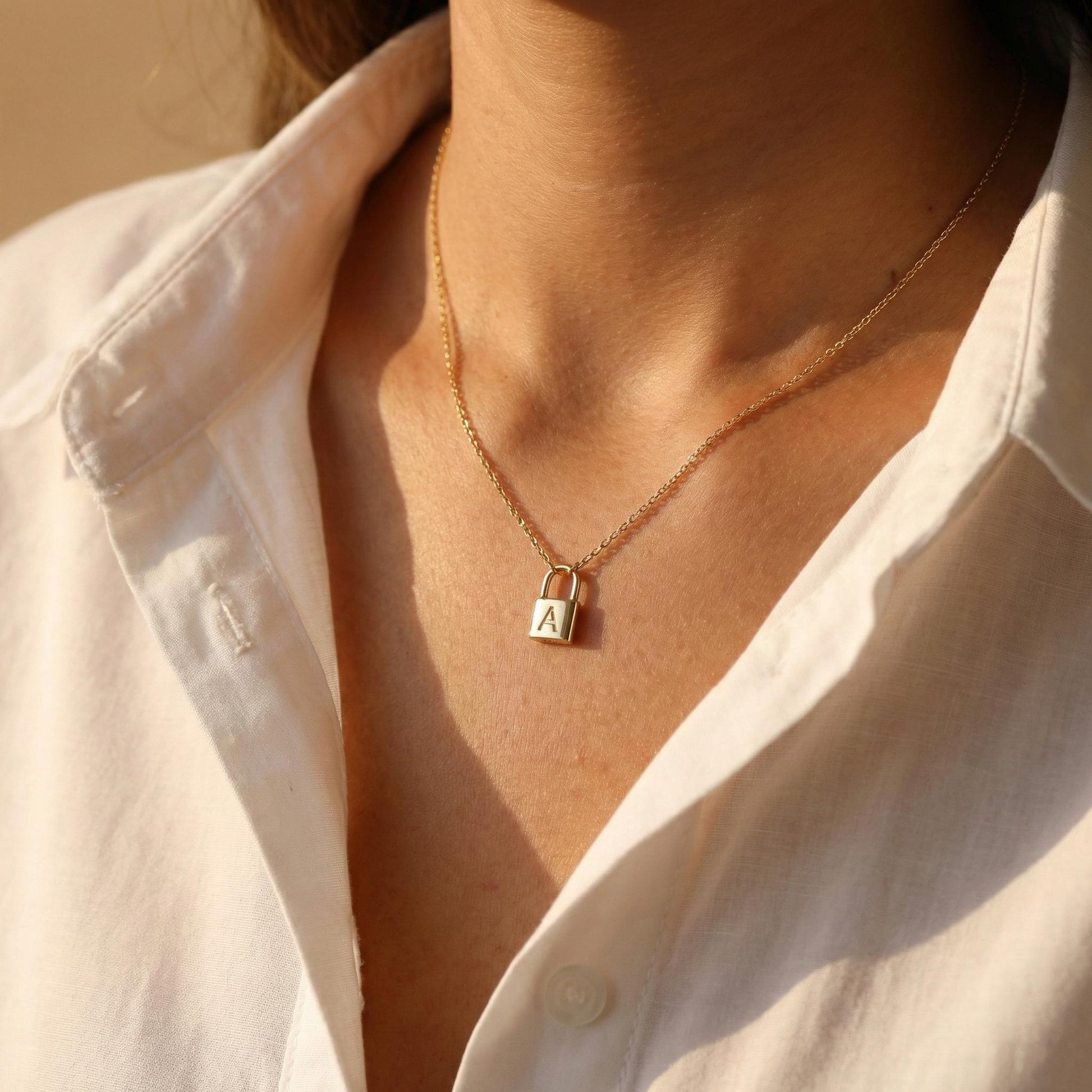 Gold padlock necklace with engraved initial letter A, dainty minimalist personalized jewelry gift for her, Mother's Day custom pendant on model.