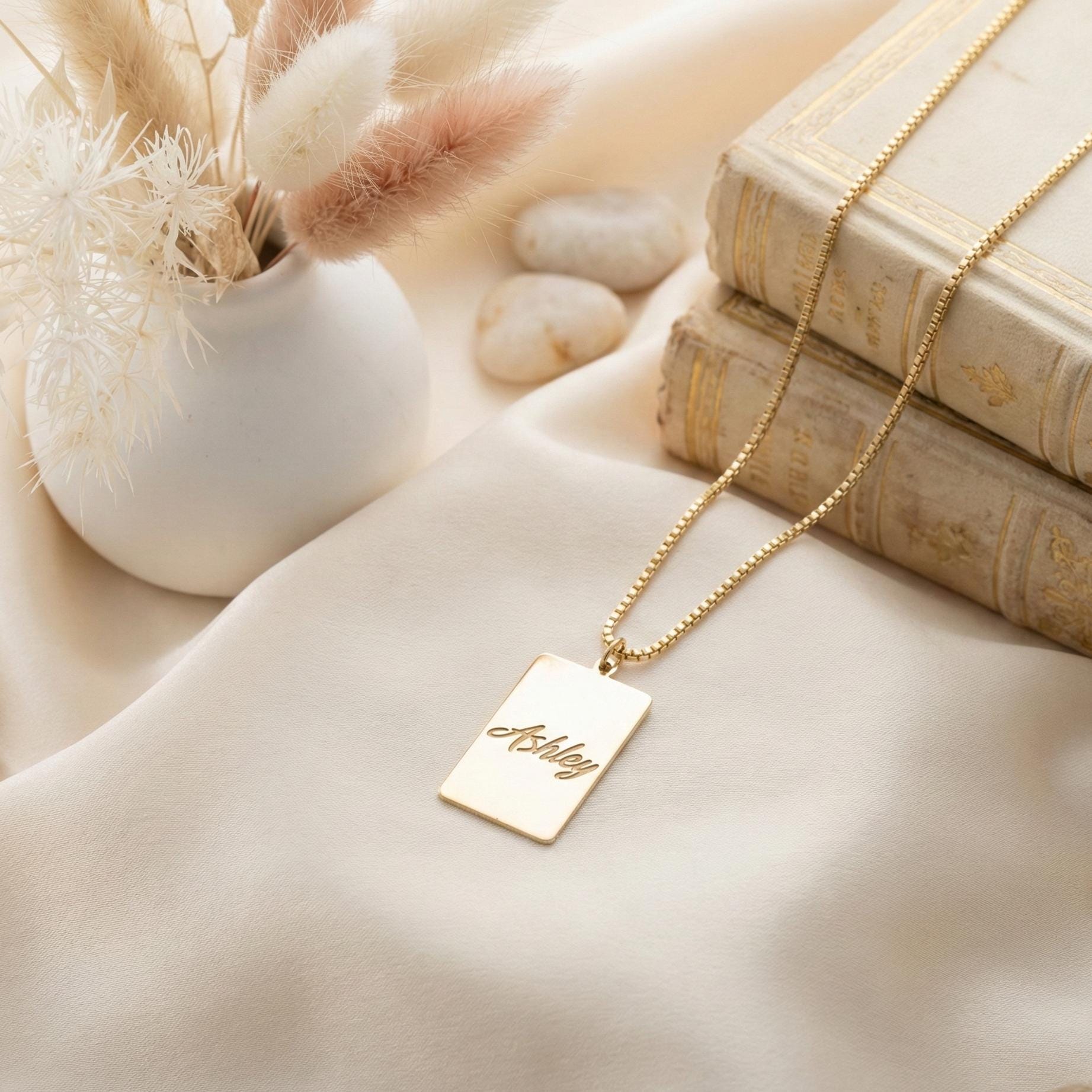 Gold vertical bar necklace on a model's neck, personalized with the engraved name Ashley in cursive font. Minimalist rectangular pendant gift for mother's day.