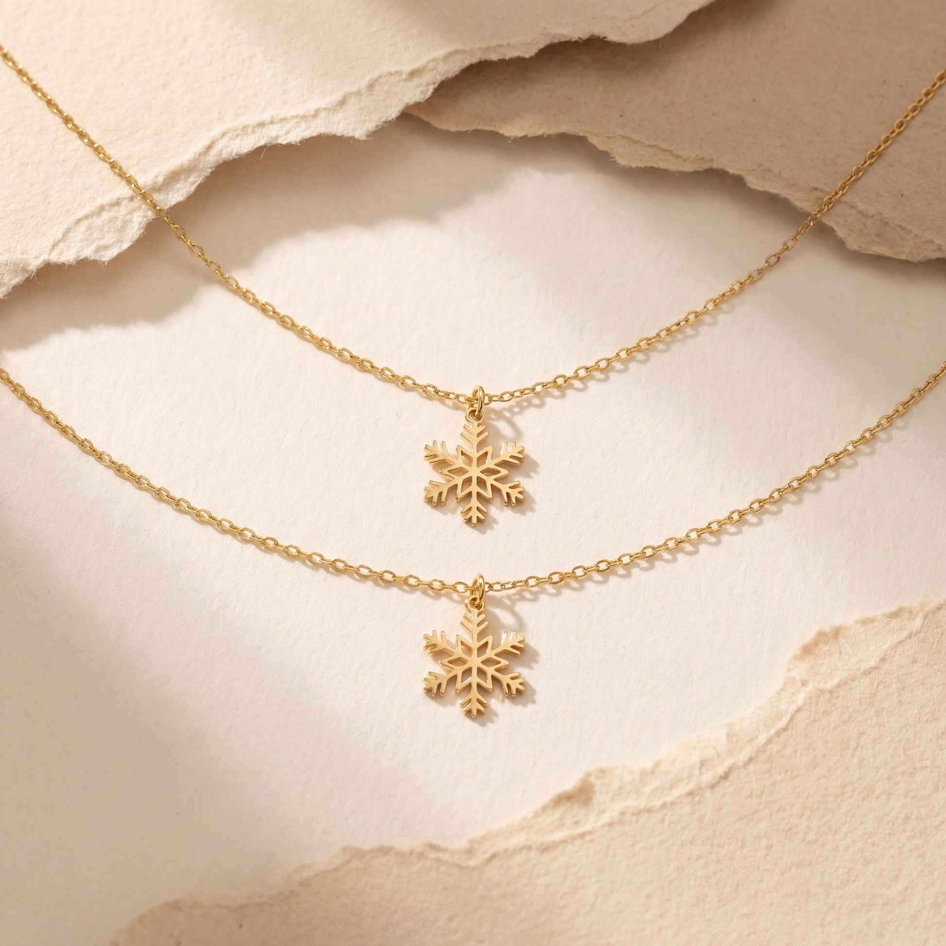Dainty 14K gold plated snowflake pendant necklace resting elegantly on a woman's collarbone, showing a minimalist geometric jewelry design perfect for a unique Mother's Day gift or layered everyday wear.
