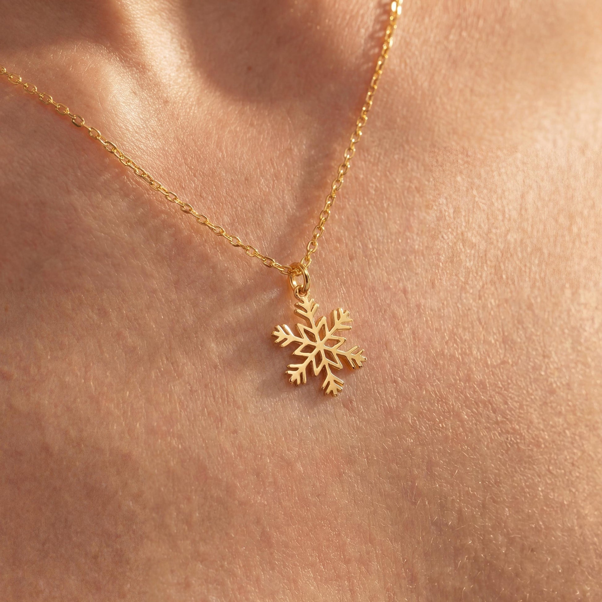 Dainty 14K gold plated snowflake pendant necklace resting elegantly on a woman's collarbone, showing a minimalist geometric jewelry design perfect for a unique Mother's Day gift or layered everyday wear.