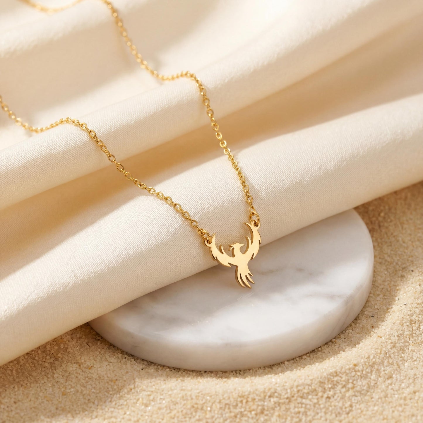 Minimalist gold phoenix pendant necklace worn on a woman's collarbone in warm sunlight, symbolizing rebirth and strength, ideal for Mothers Day gifting