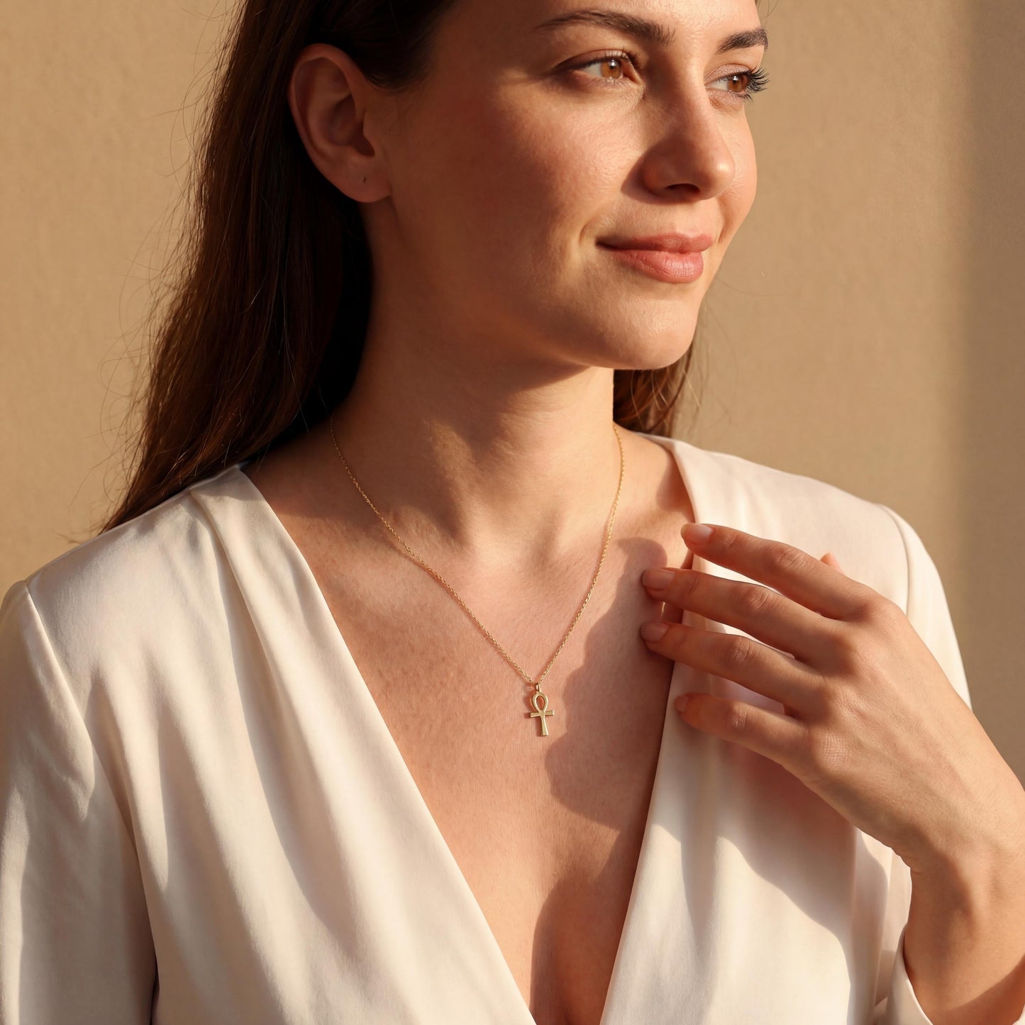 Minimalist Ankh necklace worn by a woman, dainty Egyptian cross key of life pendant resting on chest in natural sunlight, elegant everyday jewelry.