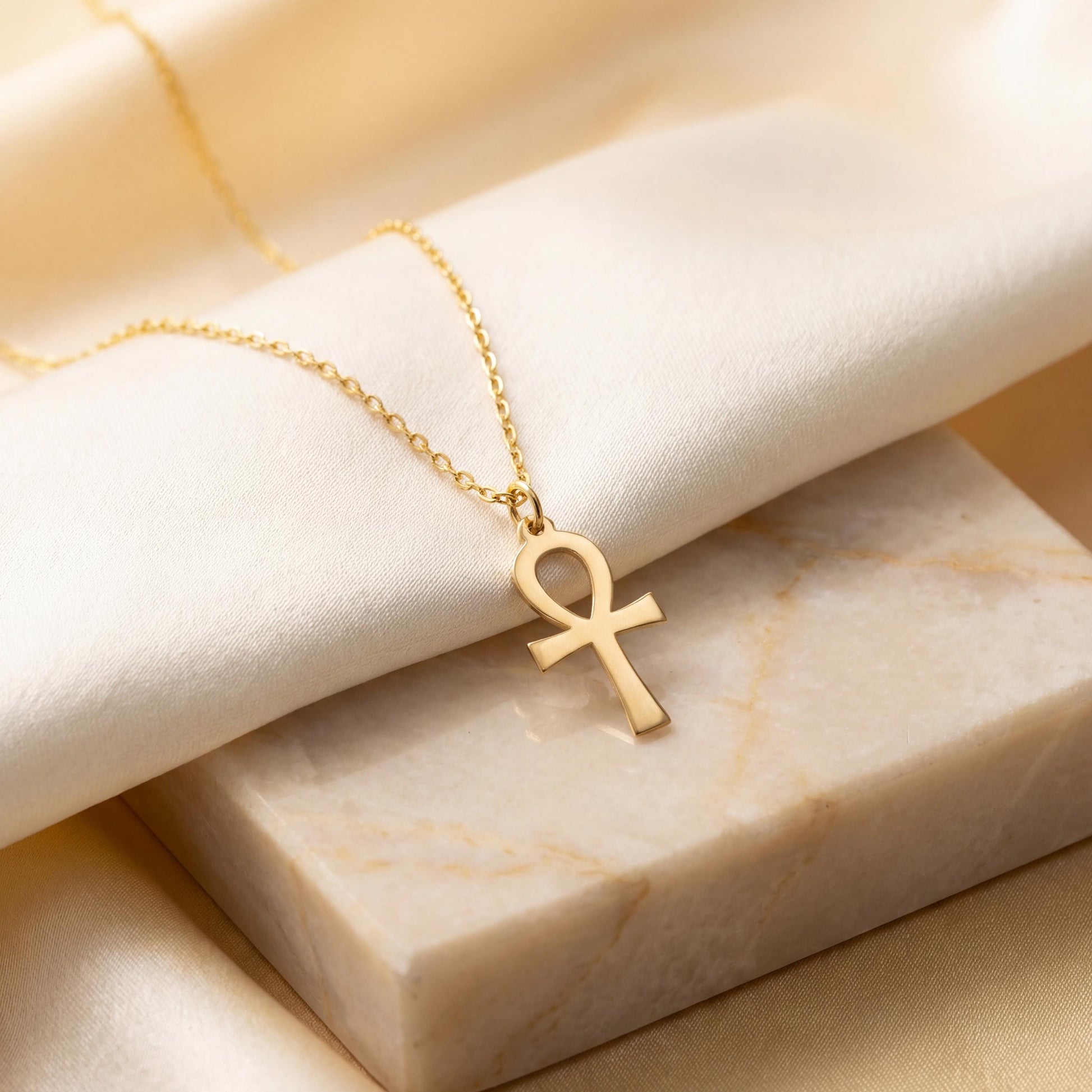 Minimalist Ankh necklace worn by a woman, dainty Egyptian cross key of life pendant resting on chest in natural sunlight, elegant everyday jewelry.