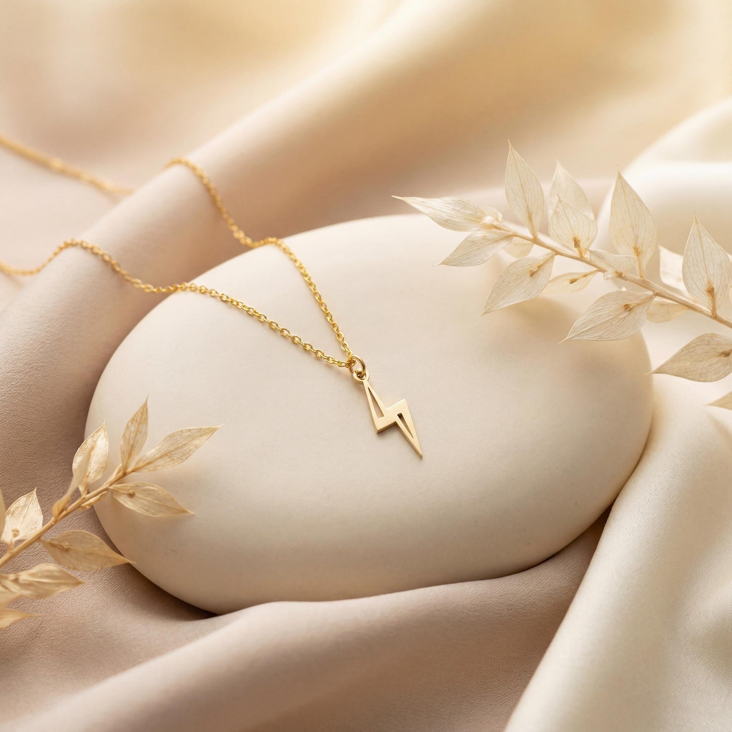 Close-up of a delicate minimalist 14k gold plated lightning bolt pendant necklace worn by a woman in a white shirt, glowing in soft sunlight.